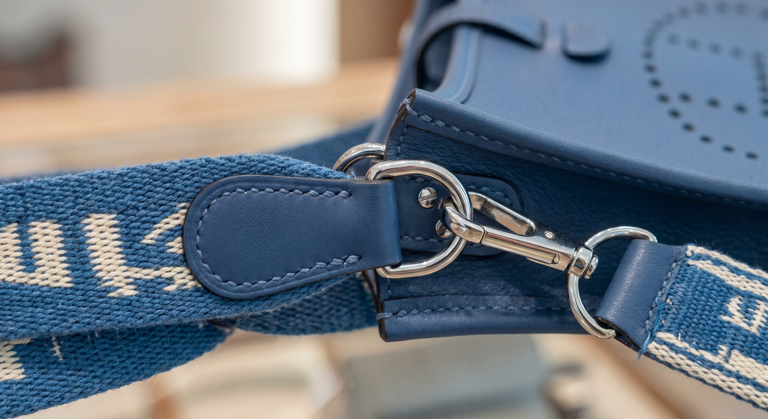 Detail showing the canvas strap and hardware attachment points of a Hermès Evelyne TPM
